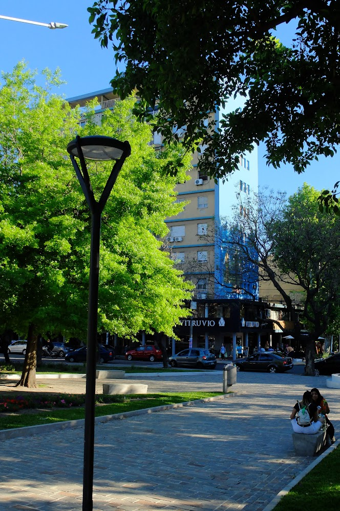 La plaza también funciona como centro urbano: vereda, bancos, comercios y sombra.